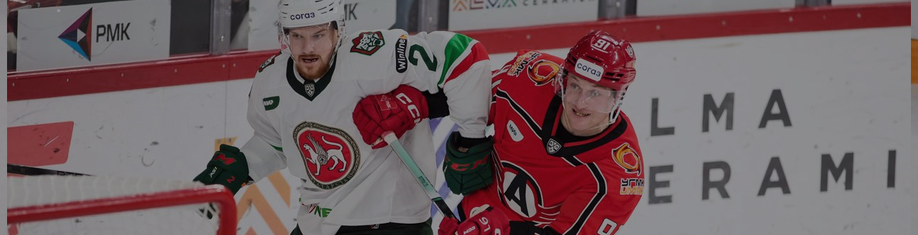 Изображение двух хоккеистов в движении на ледовой арене. Один игрок в зеленой форме, другой в красной. На заднем плане видны рекламы и разметка катка