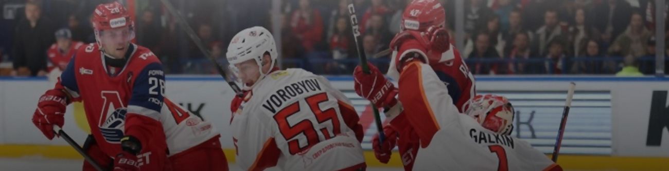 Хоккейный матч: игроки в красно-белой и бело-красной формах на льду. Один игрок вратарь с поднятой рукой, другой игрок в шлеме с цифрами 55 на спине. Трибуны полные зрителей